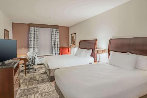 a hotel room with two beds and a flat screen tv at Hilton Garden Inn Granbury in Granbury
