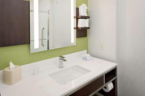 y baño con lavabo blanco y espejo. en Hilton Garden Inn DFW Airport South, en Irving