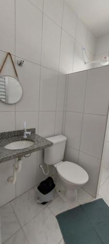 ein weißes Bad mit einem WC und einem Waschbecken in der Unterkunft Pousada Aconchego Ocian in Praia Grande