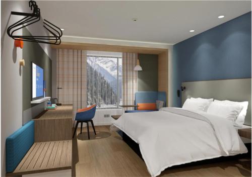 Holiday Inn Express Jiuzhaigou, an IHG Hotel في جيوتشايقو: غرفة نوم بسرير كبير وتلفزيون