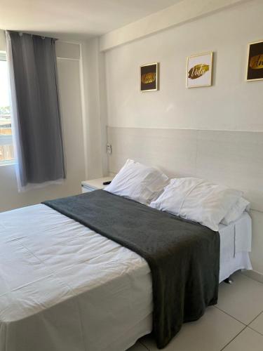 um quarto com uma cama grande e lençóis brancos em Flat na Orla de Tambaú em João Pessoa