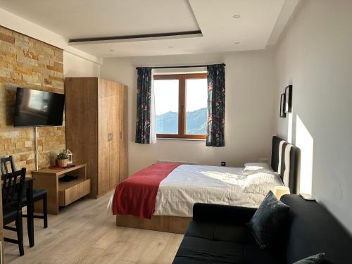 a bedroom with a bed and a window and a couch at Nana S44 Milmari Spa&Wellness in Kopaonik
