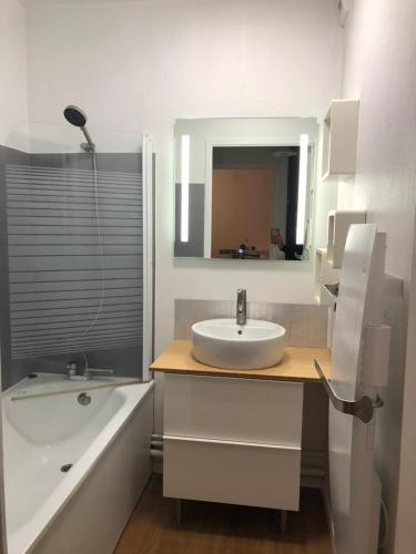 een badkamer met een wastafel, een bad en een spiegel bij T2 Cosy Mer Plage Plérin St Brieuc in Plérin