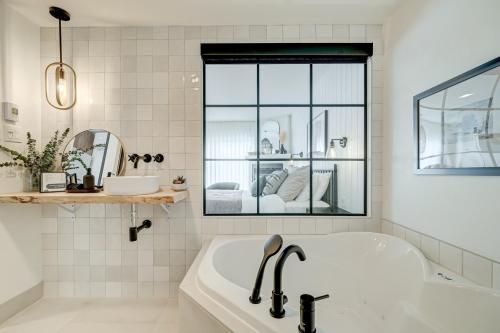 a white bathroom with a tub and a window at Les Lofts du Lac des Sables by Gestion ELITE in Sainte-Agathe-des-Monts