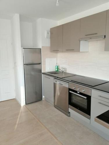 une cuisine avec un réfrigérateur et des armoires en acier inoxydable dans l'établissement Paradise - Disneyland Paris, à Chessy