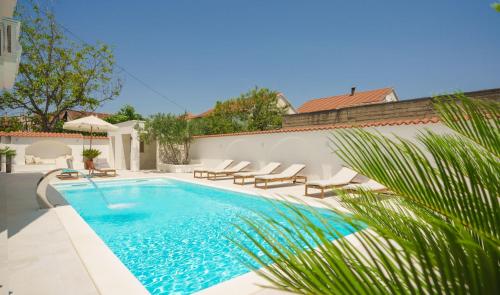 a swimming pool with lounge chairs next to a house at Villa Bianca Vodice in Vodice