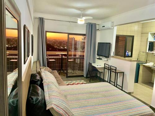a room with a bed and a view of a kitchen at Ravena 016 in Ribeirão Preto