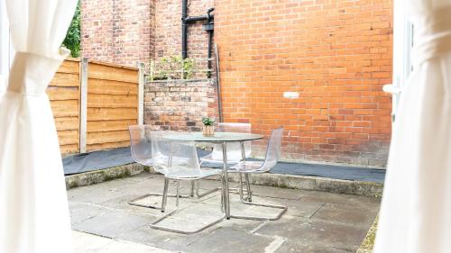 uma mesa e cadeiras num pátio com uma parede de tijolos em Amazing Entire 4 Bedroom Home em Manchester