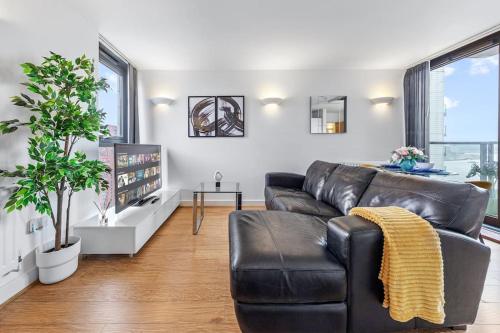 sala de estar con sofá de cuero negro en Lovely & Cosy 2 Beds London skyline view en Londres