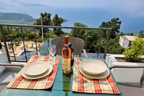 einen Tisch mit Tellern und eine Flasche Wein auf dem Balkon in der Unterkunft Apartments Oktopus in Sutomore