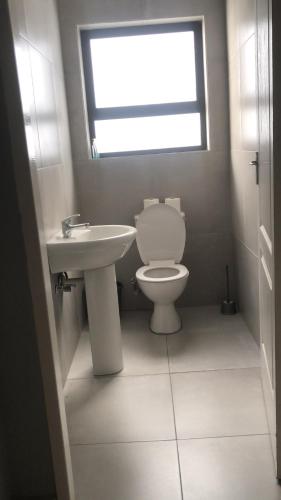 a bathroom with a toilet and a sink and a window at Emabheni Self Catering in Langstrand