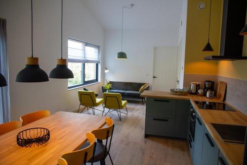 een keuken en een woonkamer met een houten tafel en stoelen bij Eco lodge Duin- unieke locatie nabij strand, duin en cultuur in Castricum