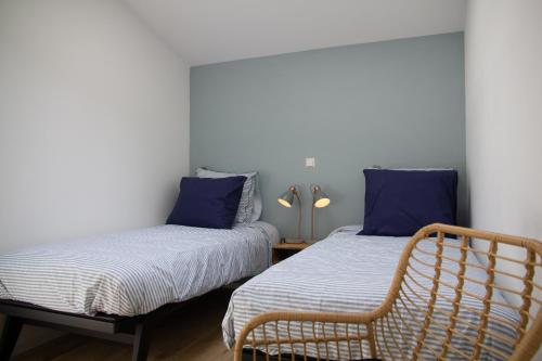 een slaapkamer met 2 bedden met blauwe kussens en een stoel bij Eco lodge Duin- unieke locatie nabij strand, duin en cultuur in Castricum