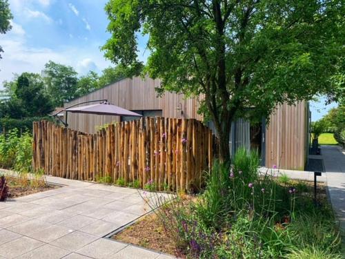 a wooden fence with an umbrella next to a tree at Eco lodge Duin- unieke locatie -strand, duin en nabij cultuursteden in Castricum