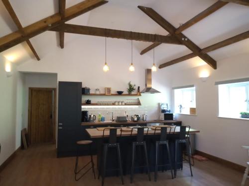 una cocina con techos de madera y un bar con taburetes en Vineyard Barns Gower, en Swansea