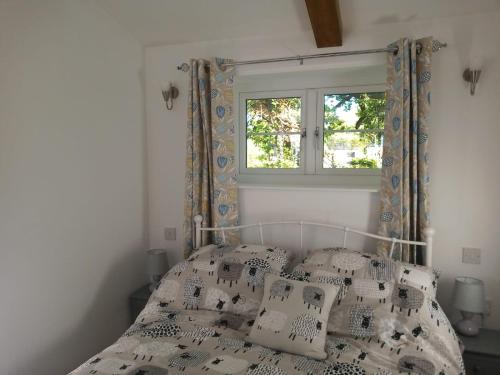 a bedroom with a bed with pillows and a window at Vineyard Barns Gower in Swansea