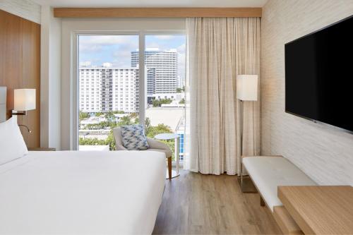 フォート・ローダーデールにあるAC Hotel by Marriott Fort Lauderdale Beachのベッドと大きな窓が備わるホテルルームです。