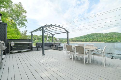 a wooden deck with a table and chairs next to the water at Les Lofts du Lac des Sables by Gestion ELITE in Sainte-Agathe-des-Monts