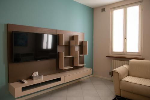a living room with a flat screen tv and a chair at Alessi Appartamenti in Desenzano del Garda