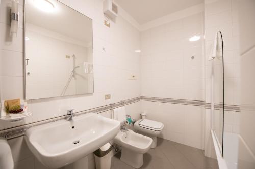 a white bathroom with a sink and a toilet at Alessi Appartamenti in Desenzano del Garda