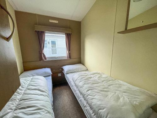 two beds in a small room with a window at Homely 8 Berth Caravan On A Great Holiday Park, Ref 46695v in Great Clacton
