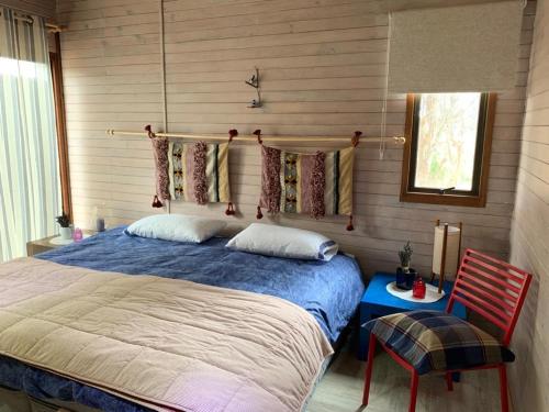 a bedroom with a bed and a chair and a window at Cabaña (entre Pichidangui y los Vilos) in Los Vilos