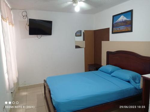 a bedroom with a blue bed and a television at Hostal SAMARY in Atacames