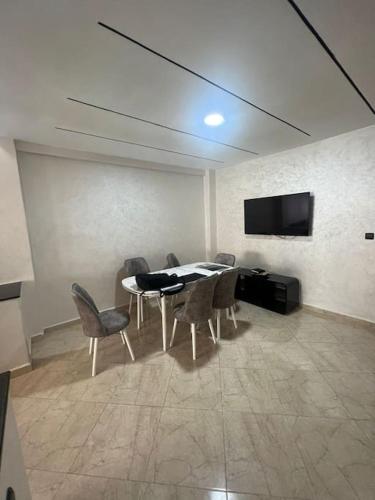 a dining room with a table and chairs and a tv at Eden Appartement avec Piscine Et Salle de Sport in El Jadida
