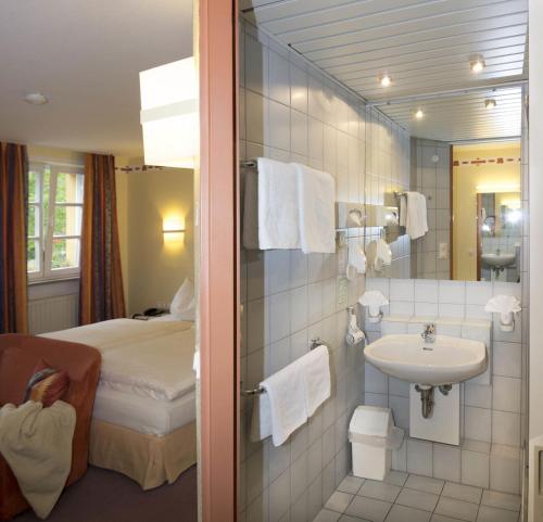 a bathroom with a bed and a sink in a room at Hotel Restaurant Lohmühle in Bayreuth
