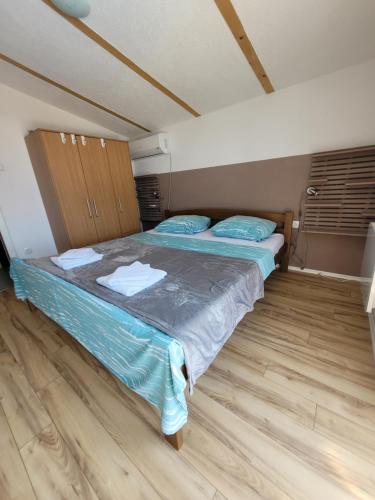 a bedroom with a bed with blue sheets and wooden floors at Villa Bosna Near Dubrovnik very beautiful Villa entirely privatized swimming pool, jacuzzi, sauna, billiard, ping-pong in Ivanica