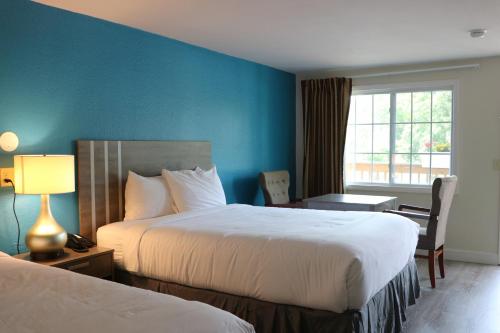 a hotel room with two beds and a desk and a window at Sunbird Cape Cod Resort in West Yarmouth