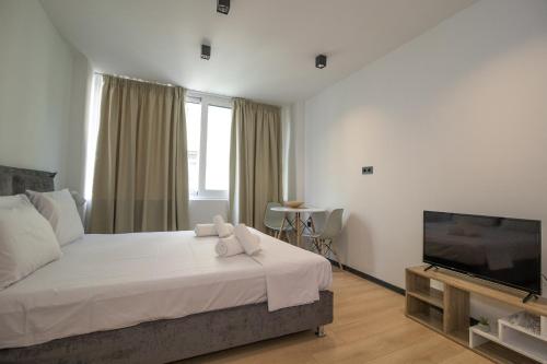 a bedroom with a large bed and a flat screen tv at Facadoro Apartments in Athens