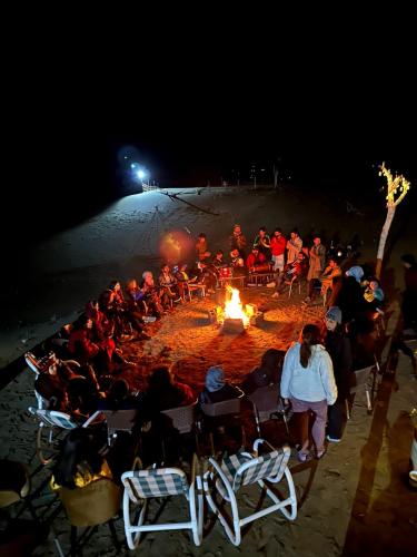 Un groupe de personnes assises autour d'un feu sur la plage dans l'établissement Oasis Resort, à Skardu