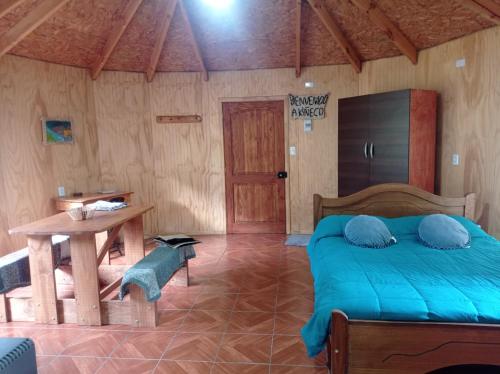 a bedroom with a bed and a table and a table at Cabaña Kiñeco y tinaja in Melipeuco