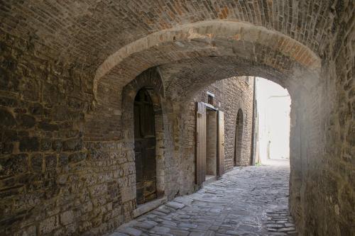 an alley in a brick wall with an archway at Monolocale centro storico in Gubbio
