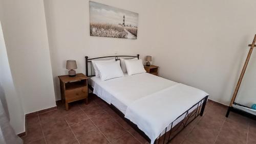 a bedroom with a bed with white sheets and pillows at Dimitra apartment with garden in Kattavia - Prassonisi in Kattavía