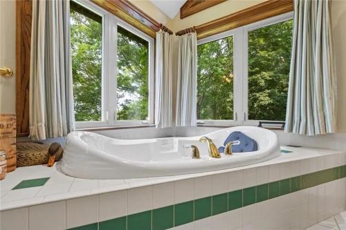 a large bath tub in a bathroom with windows at White River Mountain Manor- Million dollar view in Eureka Springs