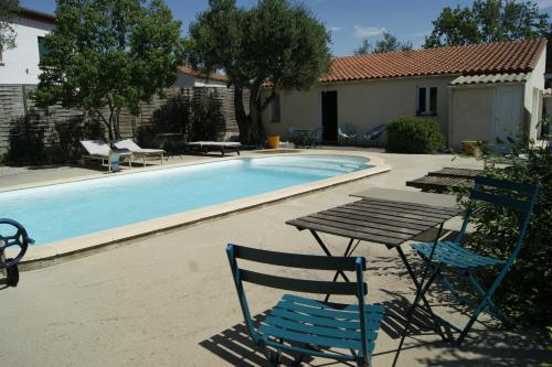 una mesa y sillas junto a una piscina en Studio avec piscine, en Corbère