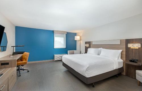 ein Hotelzimmer mit einem großen Bett und einem Schreibtisch in der Unterkunft Holiday Inn Express Atlanta Airport - North, an IHG Hotel in Atlanta