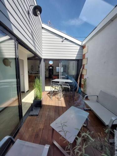 une terrasse en bois avec un canapé et une table dans l'établissement Maison ambiance loft à 2 pas du port d'Arcachon et des plages, à Arcachon