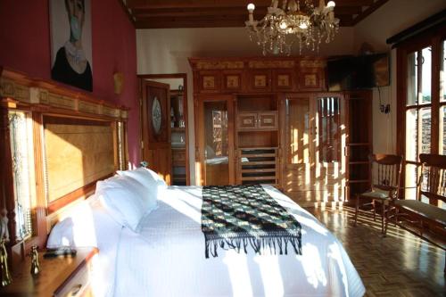 a bedroom with a large white bed with a chandelier at La Casa Baez in Pátzcuaro
