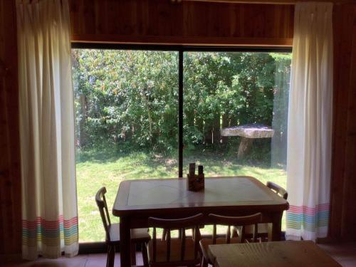 a table and chairs in a room with a large window at Cabañas Amatista Neltume in Neltume