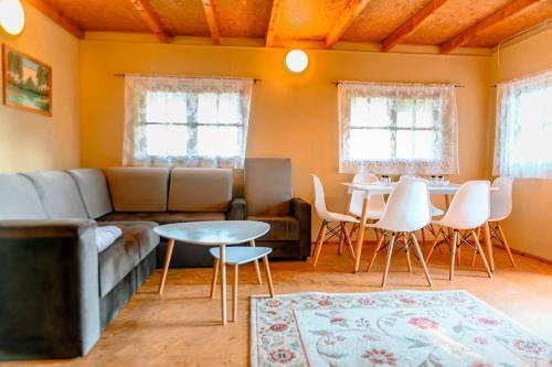 ein Wohnzimmer mit einem Sofa, einem Tisch und Stühlen in der Unterkunft Domek na Mazurach 