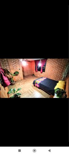 a room with a bed and a brick wall at Departamento Xolotl (Dios guía y del fuego) in Cholula