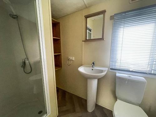 a bathroom with a sink and a toilet and a mirror at Homely 8 Berth Caravan On A Great Holiday Park, Ref 46695v in Great Clacton