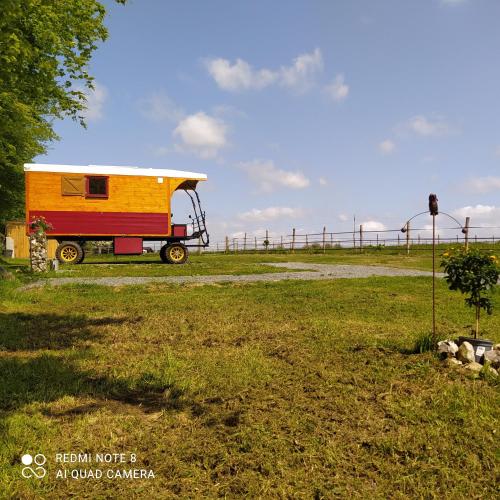 een gele en rode trailer geparkeerd in een veld bij Véritable roulotte hippomobile "LA BAILLEUL" in Mentheville