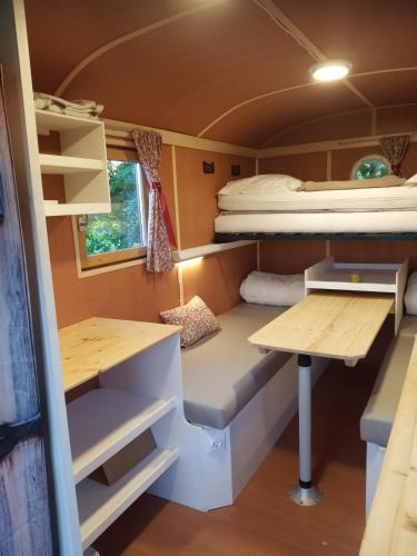une chambre avec un lit et un bureau dans une caravane dans l'établissement Véritable roulotte hippomobile 