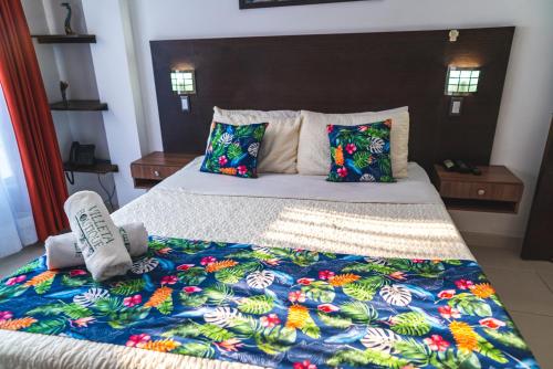 a bed with a colorful blanket and pillows on it at Villeta Boutique Hotel Spa in Villeta