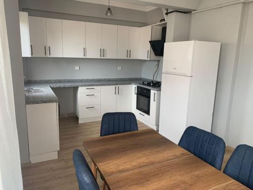 a kitchen with white cabinets and a wooden table and blue chairs at Aydın Apart in Bostancı