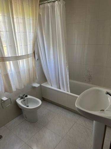 a bathroom with a toilet and a tub and a sink at Apartamentos Rial in Sanxenxo
